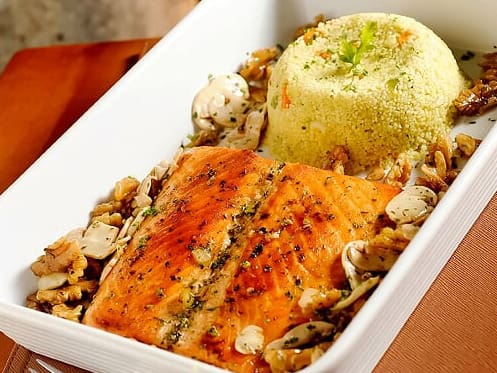 Filé de salmão fresco, grelhado com manteiga e nozes, champignon e salsinha. Acompanha arroz de brócolis e cuscuz marroquino, com brócolis, cenoura, couve-flor, alho, cebola,pimentão.