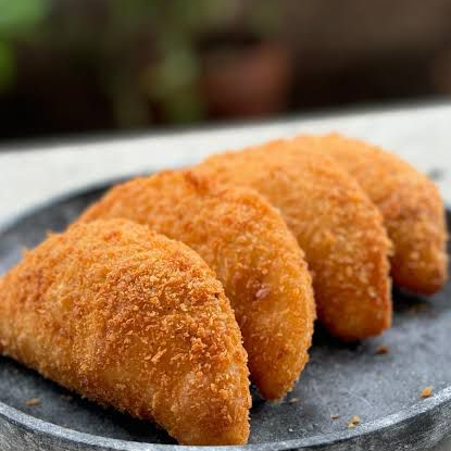 Risole crocante e douradinho, feito com massa caseira à base de farinha de trigo, leite, manteiga e ovos. Recheado com presunto picado e mussarela cremosa, temperados na medida certa. Empanado na farinha de rosca para garantir aquela crocância irresistível a cada mordida!