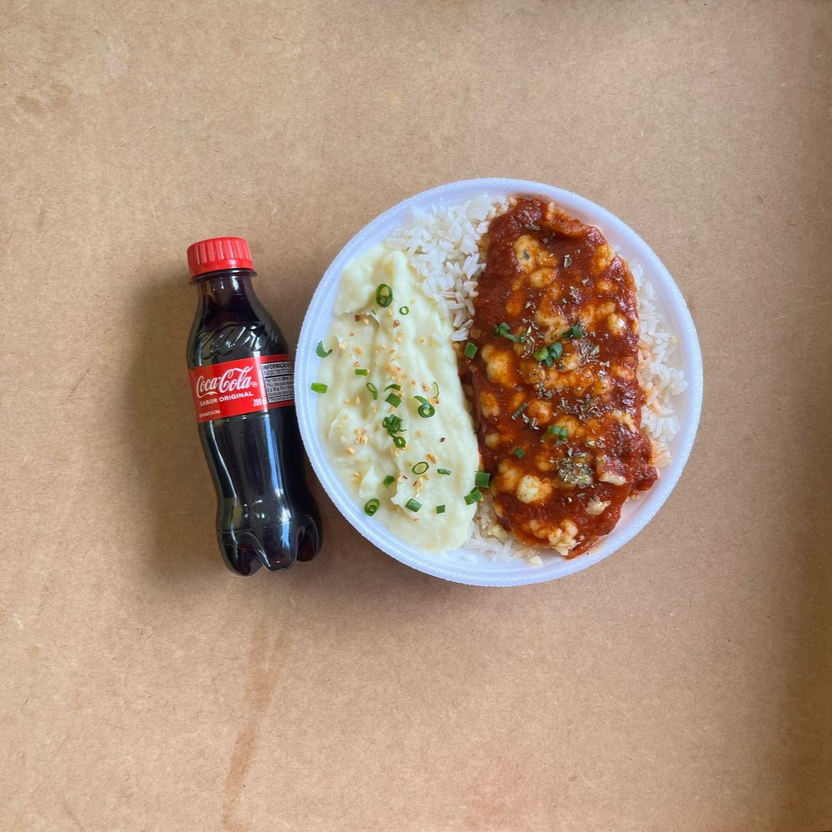 Marmita com delicioso filé de frango parmegiana (empanado na massa crocante coberto com molho de tomates e queijo) acompanhado de arroz branco e purê de batatas inglesas. Acompanha refrigerante pet Coca Cola bem gelado. Marmita indicada para 01 pessoa.