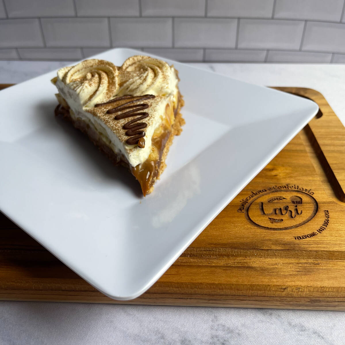 Massa de bolacha com recheio de doce de leite, banana e cobertura de nata.