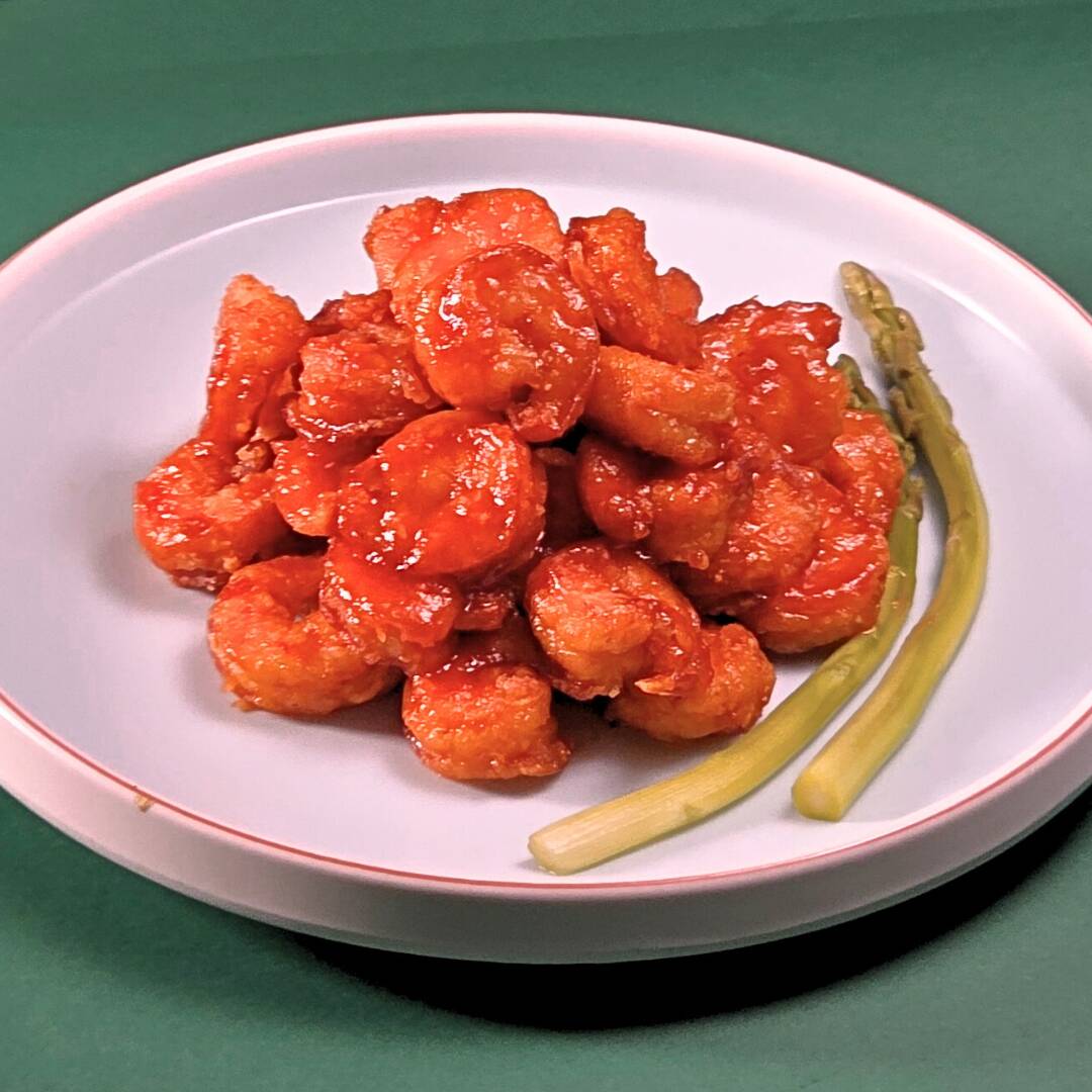 Camarões sem cascas, crocante, com molho vermelho e gergelim torrado.