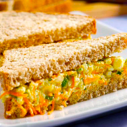 sanduiche feito no pão de caixa integral com patê de ovos , requeijão light , tomate fresco , milho , cenoura ralada . finalizado com folhas de alface fresco. .