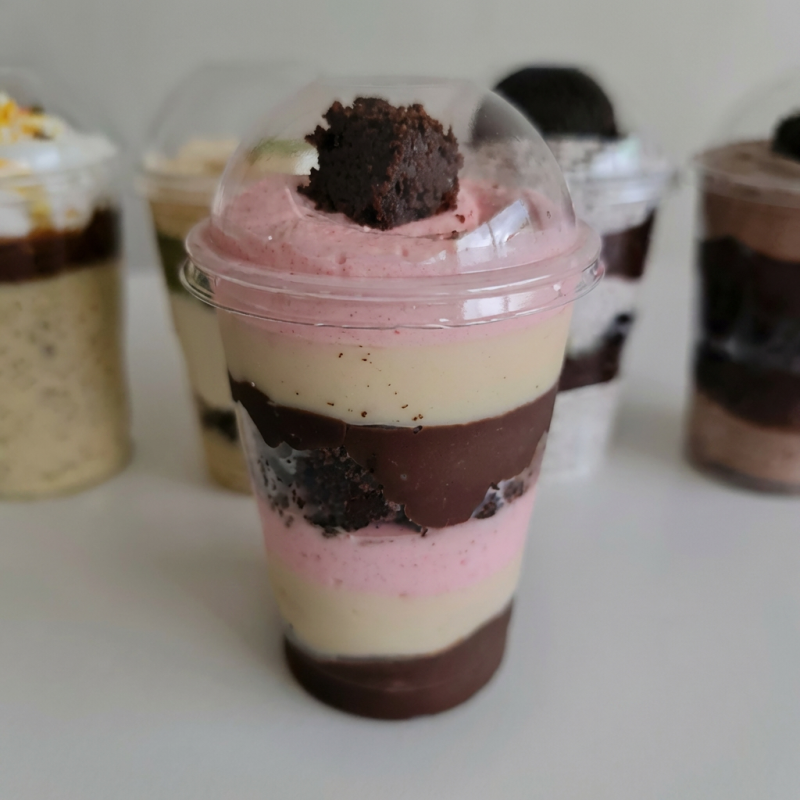 Copo da Felicidade com mousse de morango, brownie e dois brigadeiros cremosos. Explosão de sabor em cada colherada!