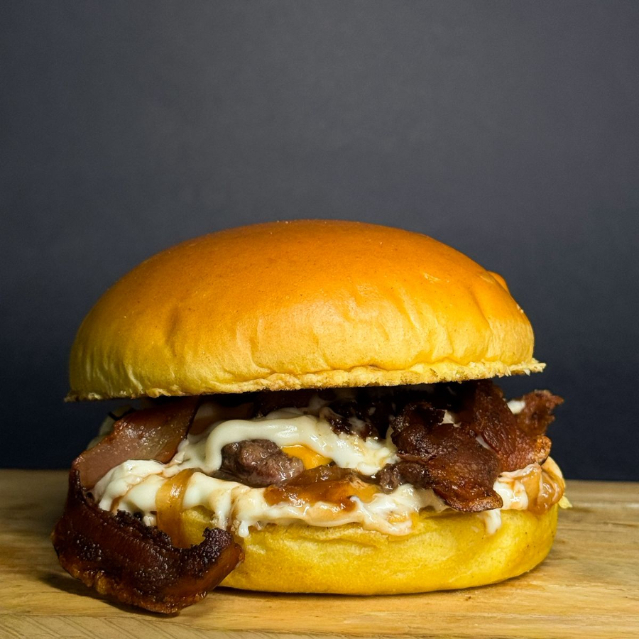 Delicioso Smash de Carne Artesanal de 80g, Pão Brioche, 2 Fatias de Queijo, Fatias de Bacon, Cebola Caramelizada e Maionese da Casa