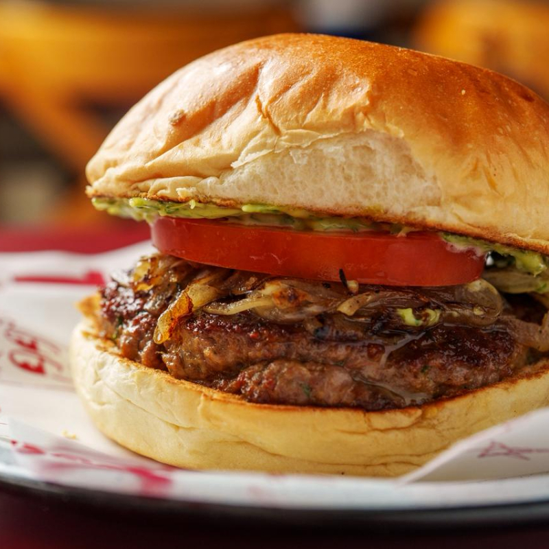 Hamburguer de cordeiro, maionese de hortelã, cebola na chapa e tomate, servido na pita ou pão de burger.