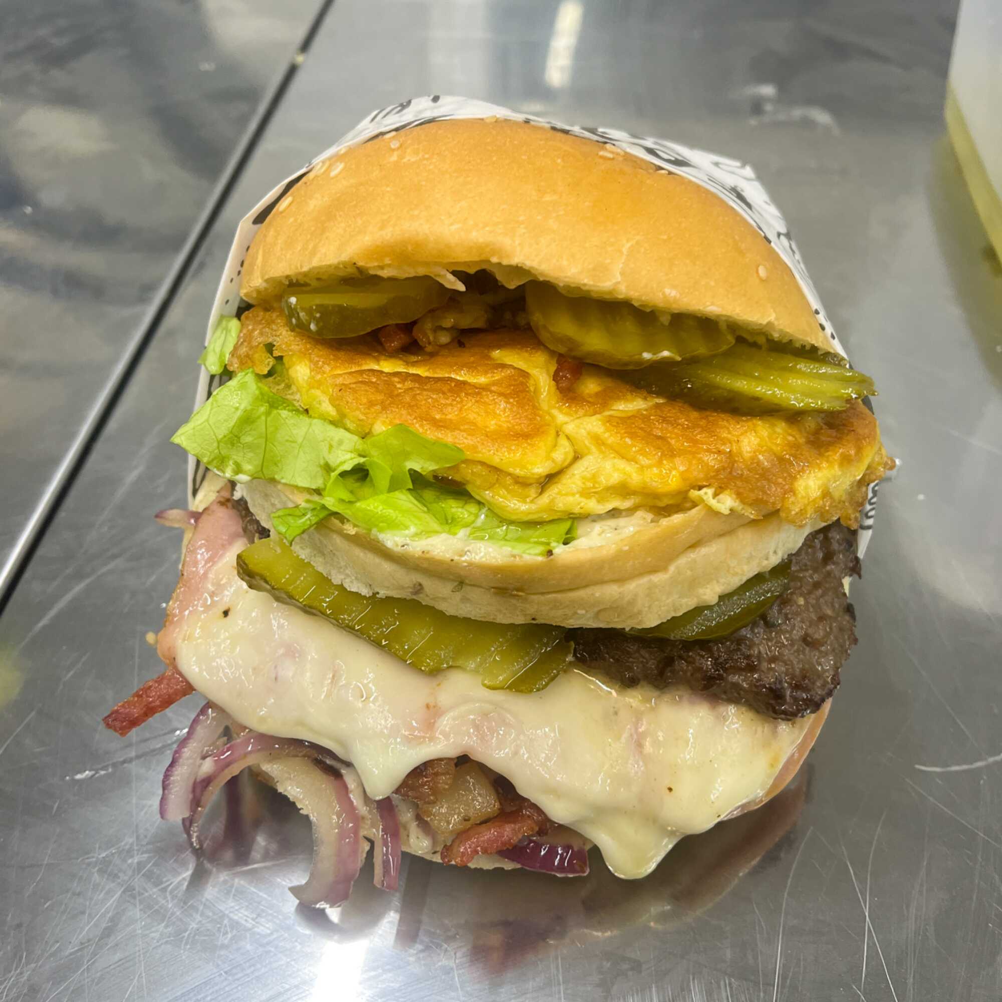Pão, maionese caseira, 2 hambúrgueres de 70g, alface, tomate, queijo, presunto, ovo, frango, cebola e pepino.