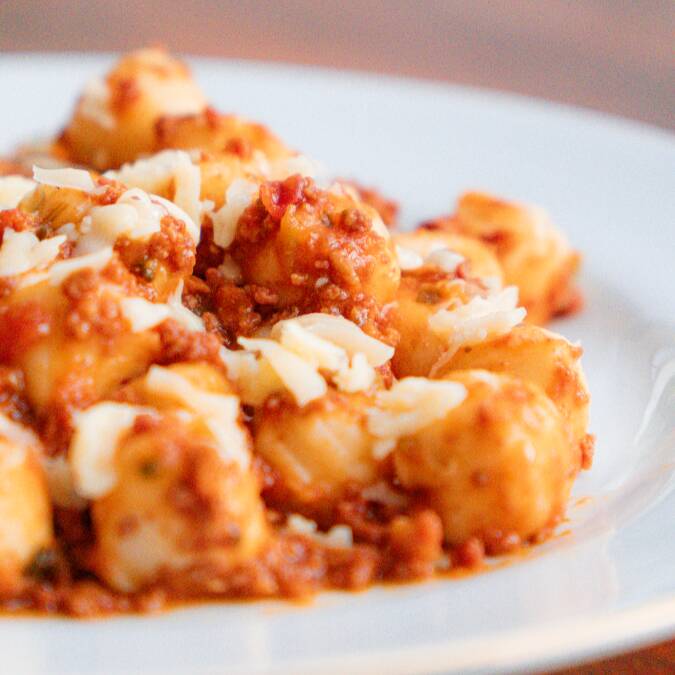 Delicioso nhoque servido com um rico molho bolonhesa feito com carne moída e especiarias aromáticas.