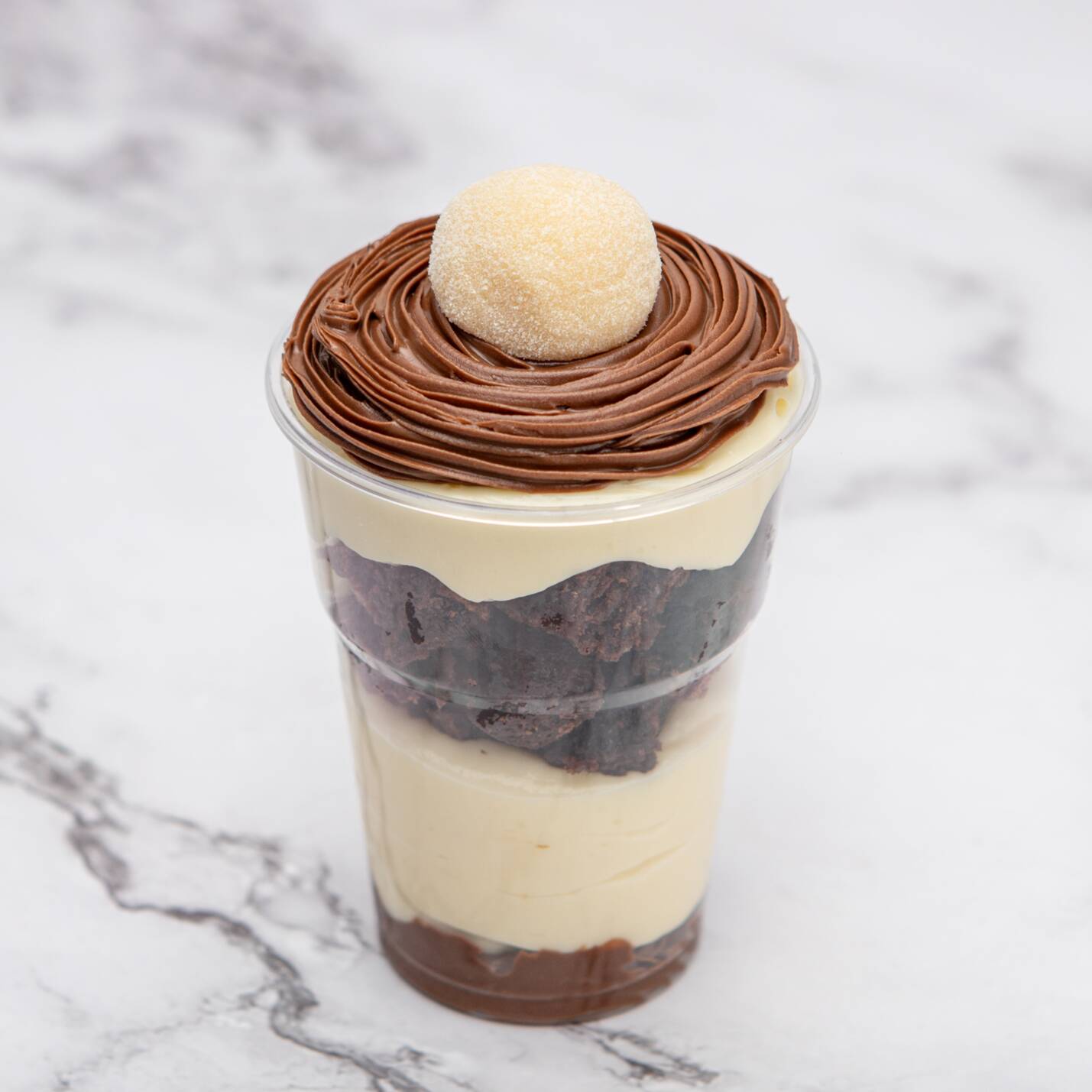 Uma deliciosa camada de creme de avelã, seguida do nosso cremoso creme de ninho, pedaços de brownie tradicional, finalizado com um brigadeiro de ninho