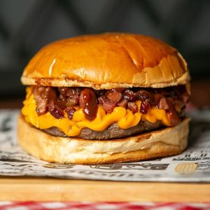 Pão de brioche, burguer de 150g, queijo cheddar, bacon, picles e maionese da casa.