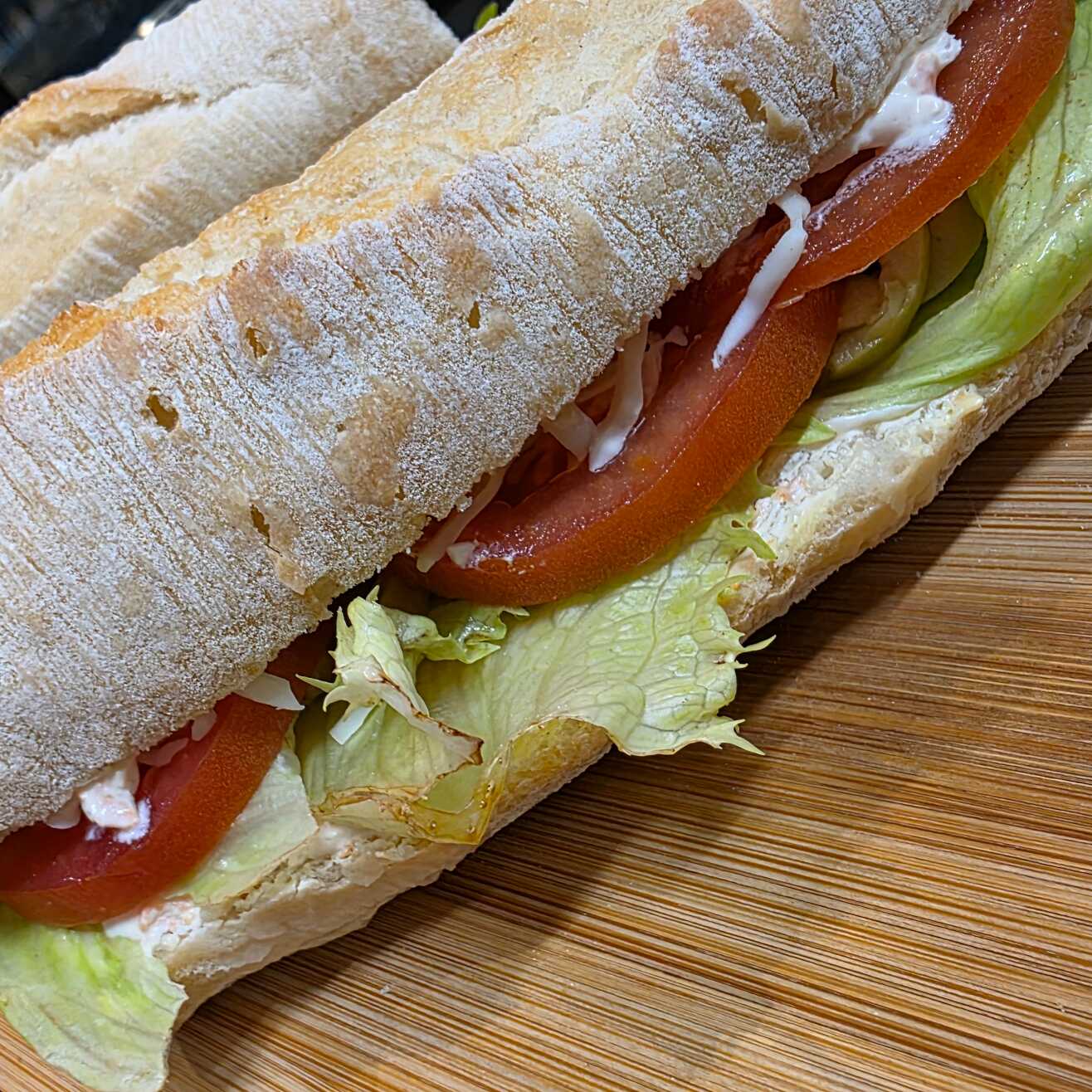 Pão ciabatta, creme de queijo com cenoura ralada, azeitonas verdes, alface americana, rodelas de tomate e queijo mussarela ralado