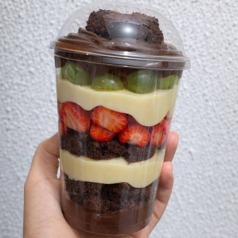 Recheio delicioso de creme branco, nosso brigadeiro cremoso, brownie super chocolatudo e frutas frescas de morango e uvas