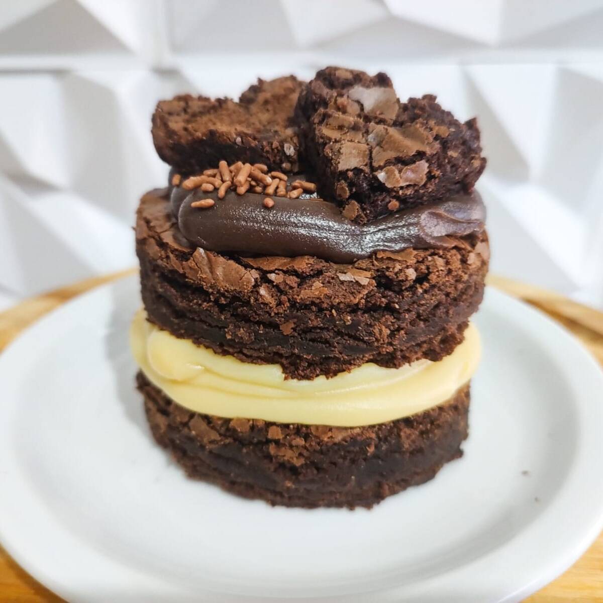 Dois discos de brownie chocolatudo, recheio cremoso de Ninho no meio e brigadeiro por cima. Uma sobremesa intensa, generosa e impossível de comer só uma colherada, medindo 8,5 x 8,5 centimetros de largura.
