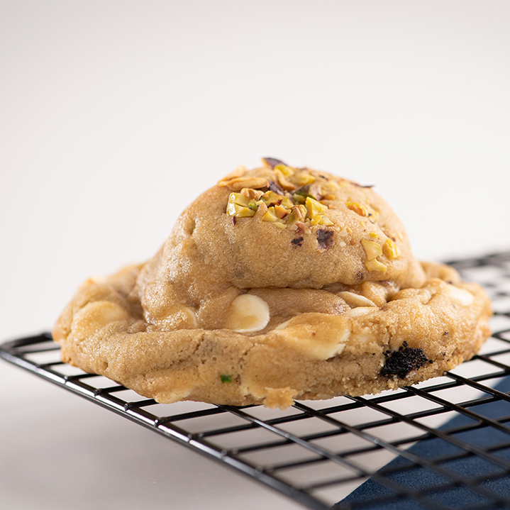 Massa com pedaços de pistache, gotas de chocolate nobre branco e recheio de ganache de pistache.