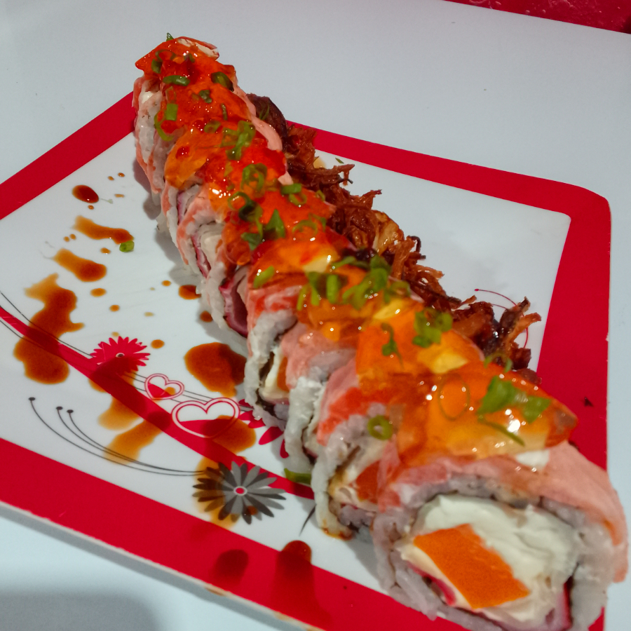 Alga revestida de arroz e gergelim torrado , recheado com kani kama cream cheese e manga coberto com manta de salmão flambado e geleia de pimenta