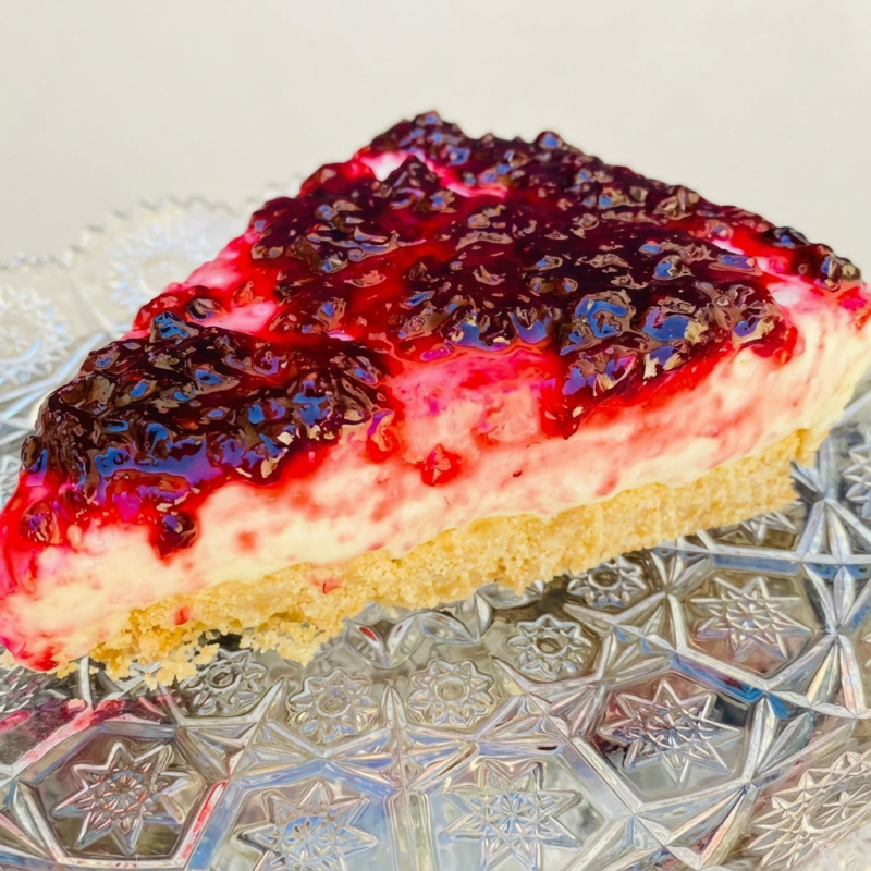 Apresentamos nossa irresistível Cheesecake de Frutas Vermelhas, um clássico da categoria 'Bolos & Tortas'. Este divino doce é meticulosamente preparado com um tradicional recheio de quatro leites, conferindo uma textura cremosa e aveludada. O grande destaque fica por conta da nossa encantadora geleia caseira, composta por frutas vermelhas frescas, que adiciona uma camada de sabor intensamente frutado e uma delicada acidez que equilibra perfeitamente a doçura do bolo. O resultado é uma sobremesa digna de aplausos, que promete seduzir seu paladar a cada mordida.