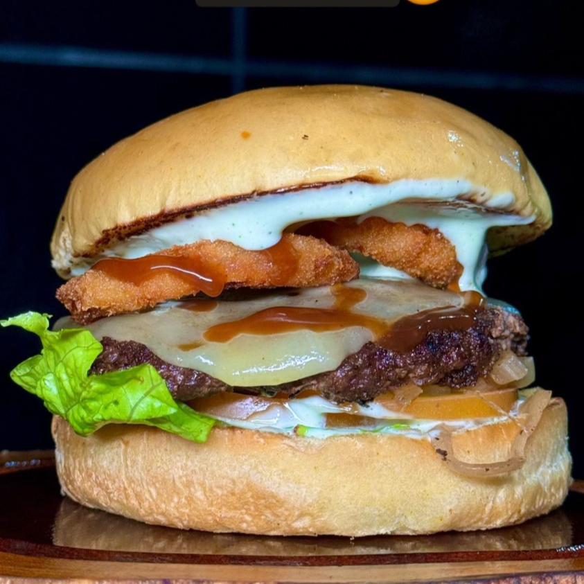 Pão amanteigado selado na chapa, Carne Artesanal 120g,Onion Rings (Anéis de cebola empanado), Queijo Mussarela,Alface, Tomate, Cebola caramelizada e molho especial. Sabor incrível