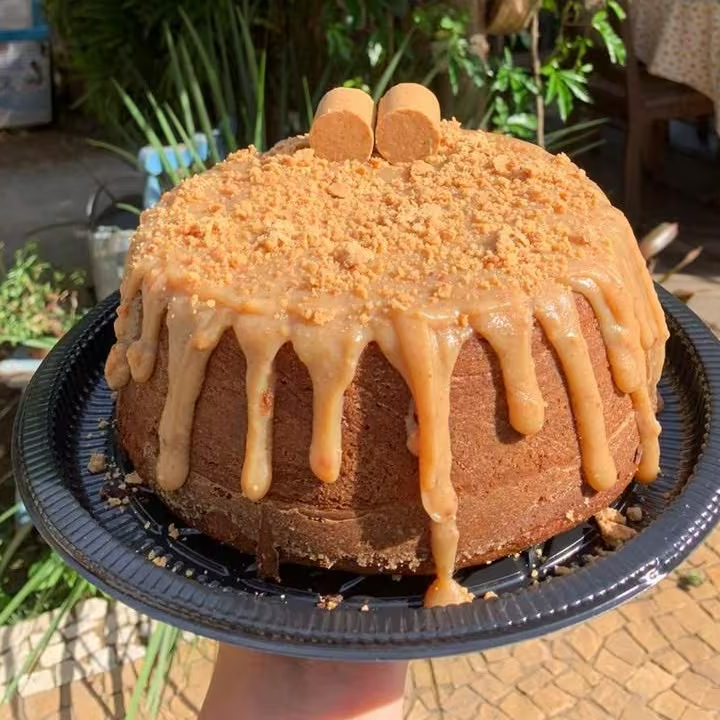 Massa: bolo de amendoim Recheio/Calda: calda de doce de leite Cobertura/Decoração: farofa de paçoca Decoração: duas paçocas rolhas