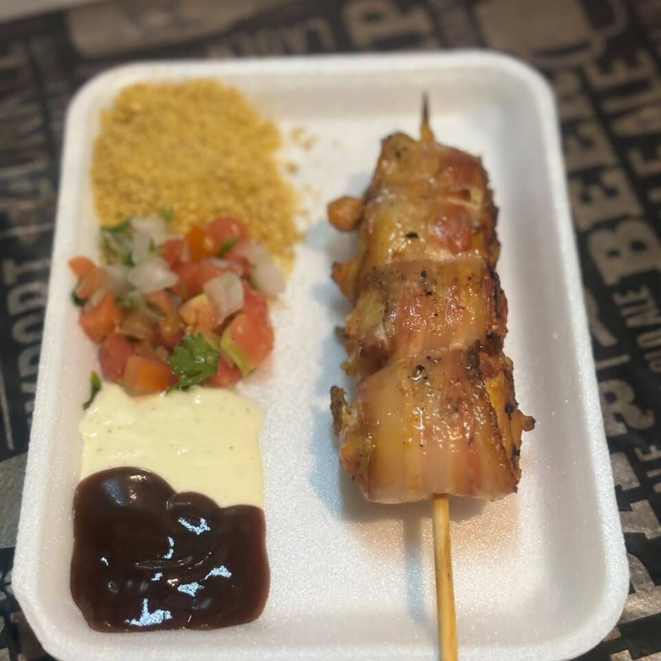 Delicioso espetinho de frango com bacon, preparado para ficar douradinho, suculento e cheio de sabor! Acompanha 4 acompanhamentos à sua escolha entre nossas opções: farofa, vinagrete, molho barbecue e creme de alho. Você escolhe seus favoritos e monta seu prato do seu jeito!