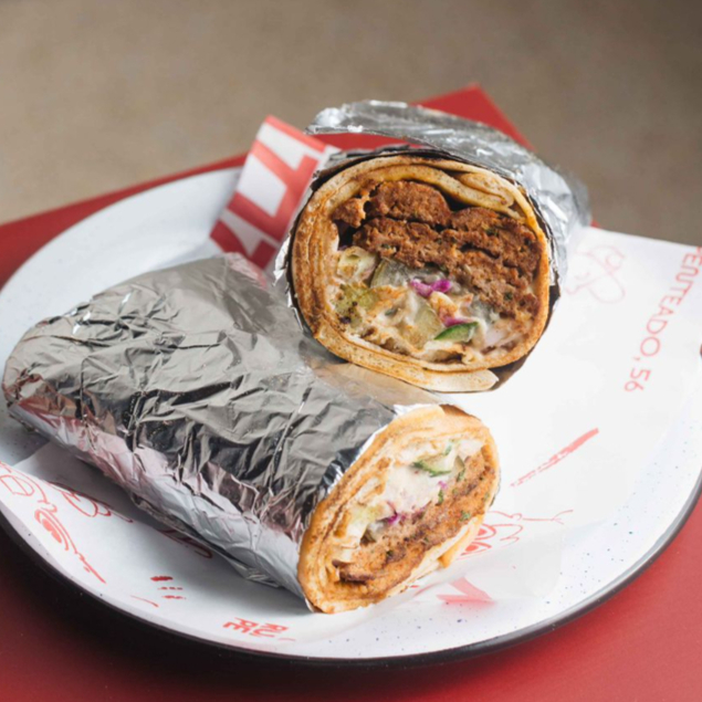 Dois espetinhos de kabab (kafta de carne bovina), salat israeli (tomates e pepinos em cubos), hummus, tehina, repolho e picles de pepino, servidos na lafa.