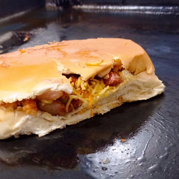 Escolha entre bacon ou Calabresa, 1 vina (perdigão), maionese (industrial dajuda), cenoura ralada, milho, tomate, cebola, pimentão, farofa, batata-palha.