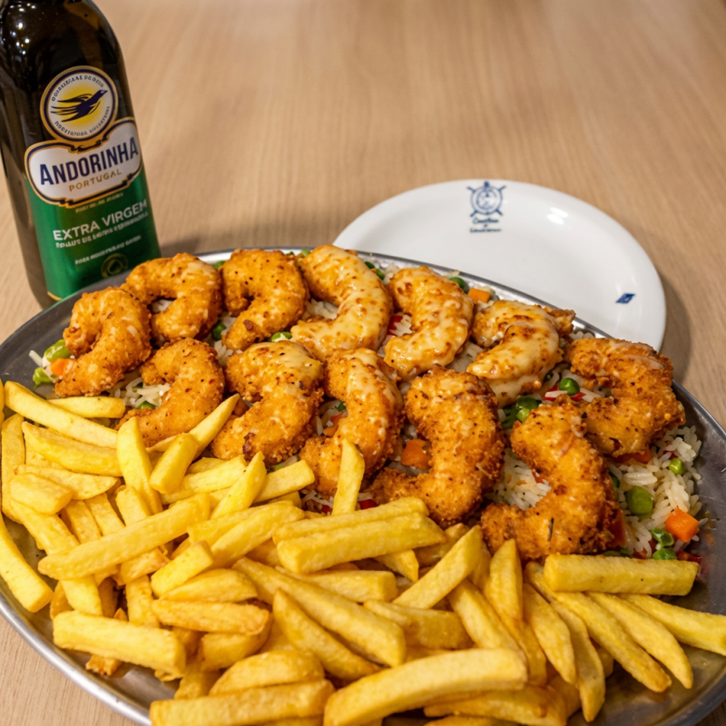Camarões médios, caprichosamente empanados à milanesa com farinha de pão italiano, deitados no arroz à grega, cobertos com mussarela de primeira e depois gratinados na salamandra. Acompanha batatas fritas.