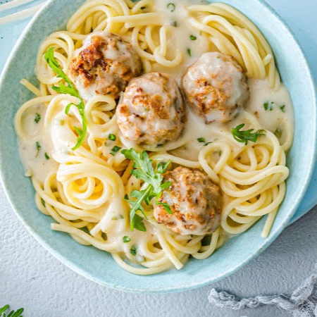 Macarrão com suculentas almôndegas de frango caseiras e o nosso cremoso molho bechamel.