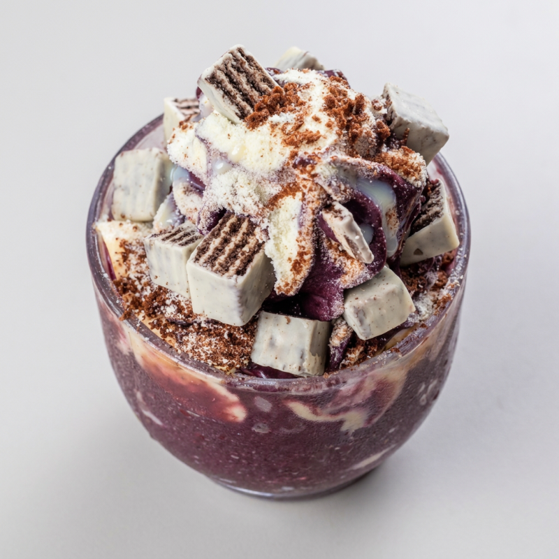 Creme de açaí acompanhado de banana, leite condensado, leite em pó, Ovomaltine e Bis no pote.