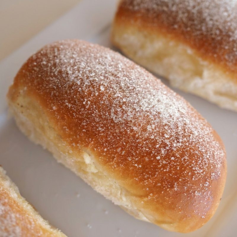 Macio e levemente dourado, esse pão doce encanta com sua cobertura de açúcar cristal, trazendo o equilíbrio perfeito entre sabor e simplicidade.