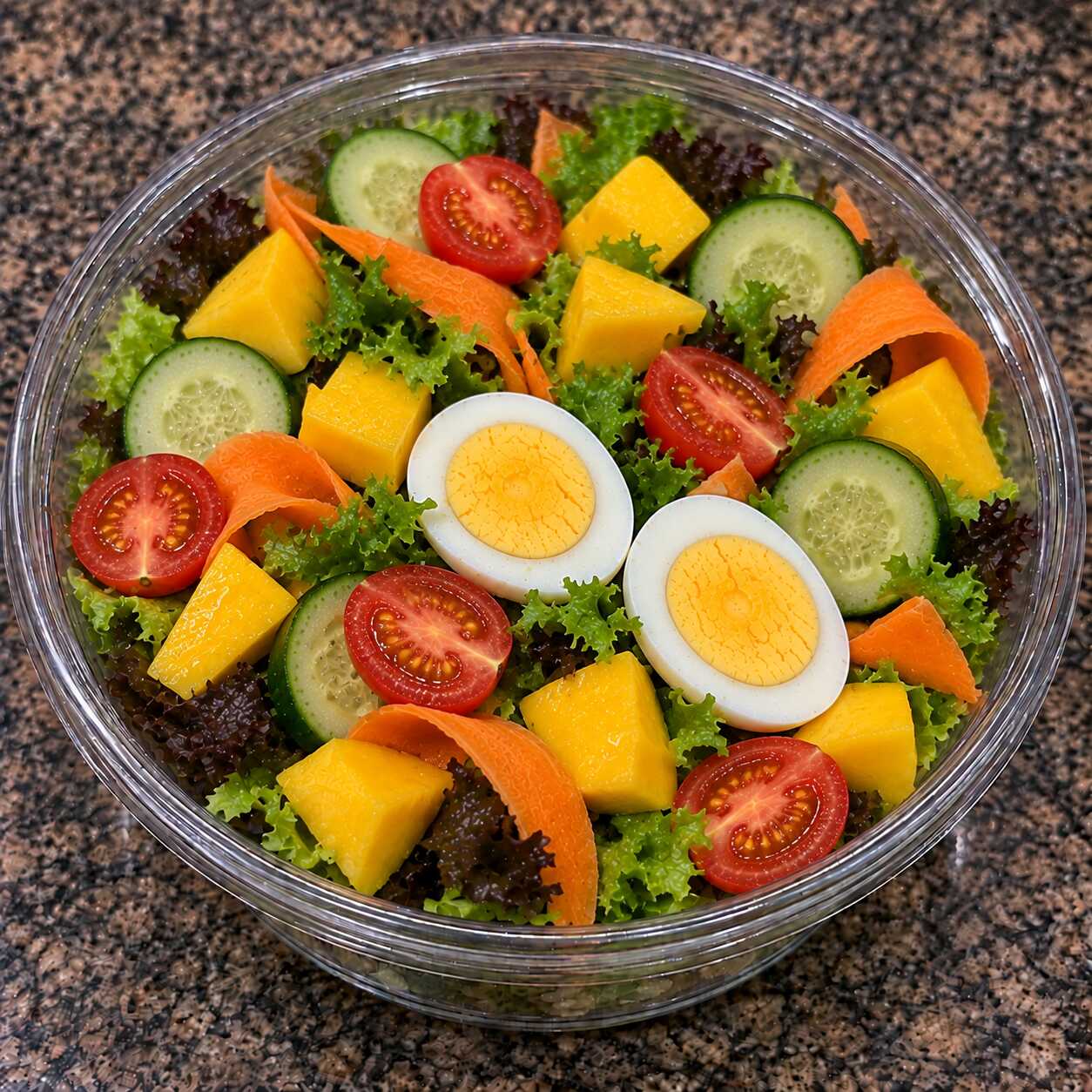 Fresca, colorida e com um delicioso toque tropical: ovos cozidos, manga, folhas, tomate-cereja, cenoura e pepino.