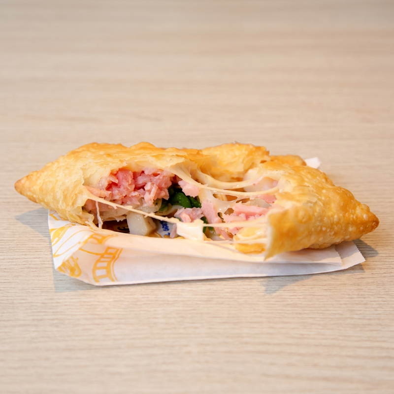 Pastel frio bem sequinho e crocante, recheado no estilo pizza, com queijo muçarela derretido, presunto e um toque de orégano, trazendo aquele sabor clássico de pizza em cada mordida.