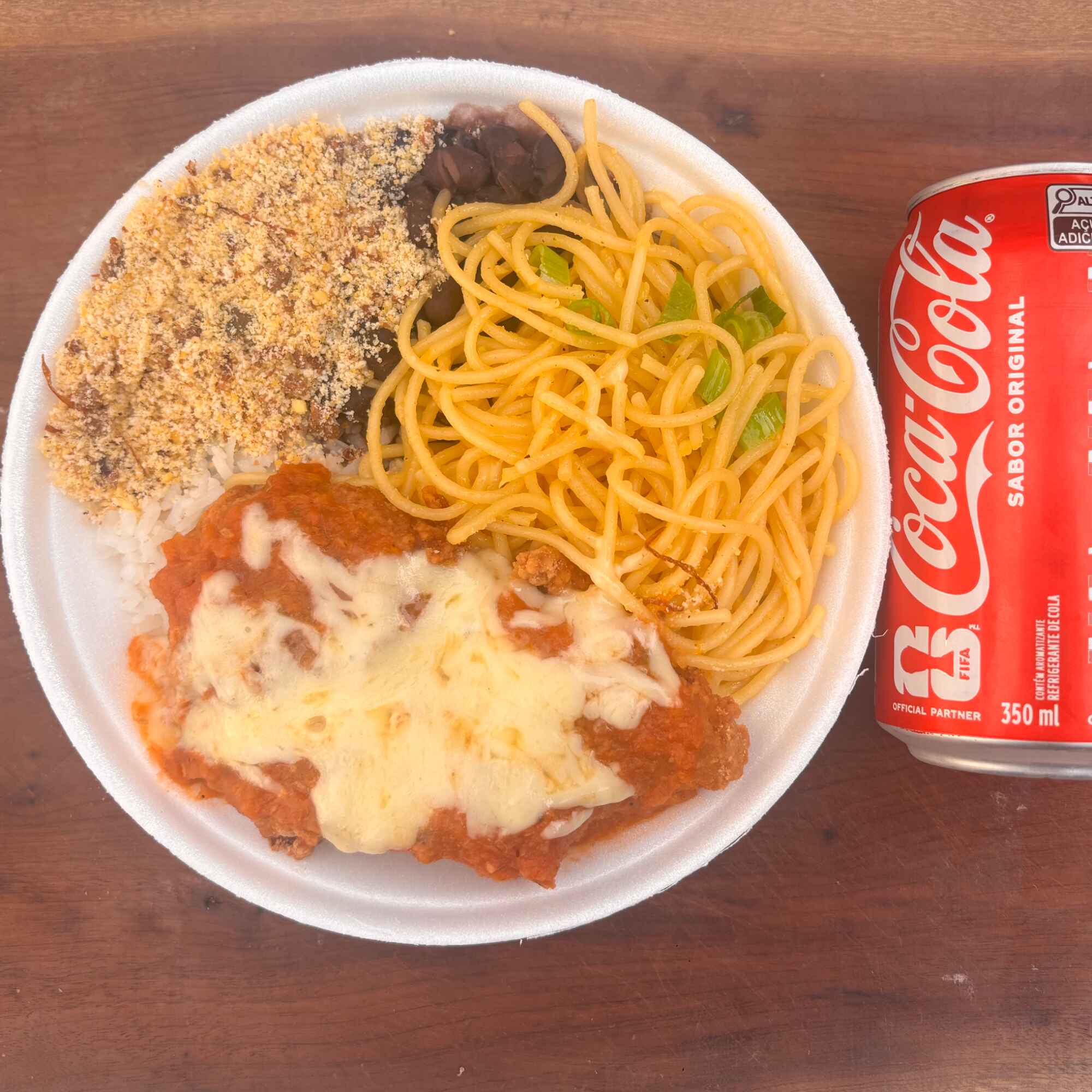 Arroz soltinho, feijão bem temperado, farofa, macarrão alho e óleo e filé de frango à parmegiana acompanha coca cola lata original.