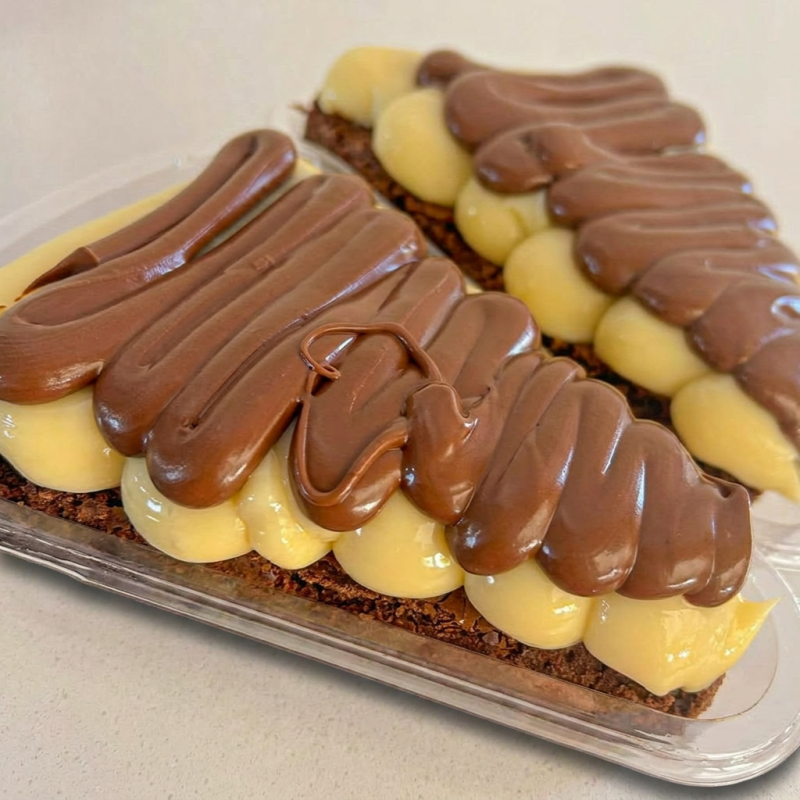 Uma fatia generosa do brownie artesanal da Santa Dopamina, macio por dentro e intenso em chocolate, finalizada com um brigadeiro cremoso de Ninho e uma camada generosa de Nutella. Uma sobremesa super cremosa, rica em chocolate e impossível de resistir. (Aqueça 30 segundos no microondas e surpreenda-se com esta delícia que vai alegrar seu Dia)