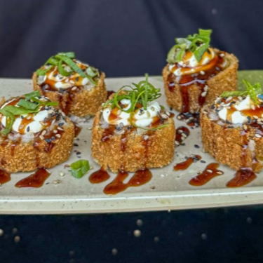 Delicioso hot roll feito com salmão grelhado, arroz oriental e cream cheese envolto por nori, empanado com farinha panko e frito, coberto por cream cheese, tarê e gergelin. (Acompanha hashi + 1 sache de molho shoyo + 1 sache de tarê)