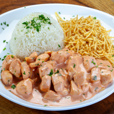 Clássico strogonoff de frango com molho cremoso, servido com arroz e batata palha.