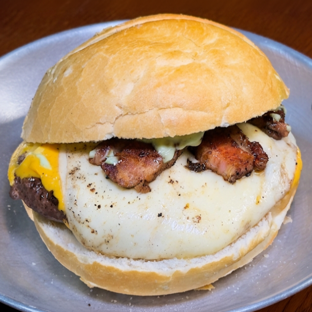 Pão crocante, 120g de hambúrguer, maionese da casa, queijo cheddar derretido com uma camada de mussarela e fatias de bacon crocante.