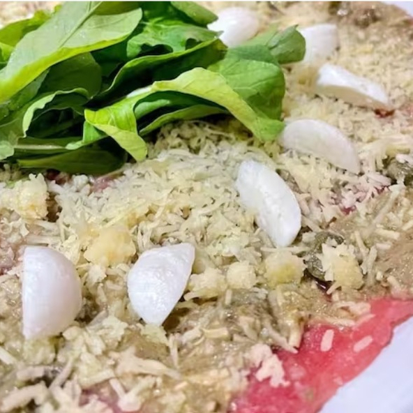 Delicioso aperitivo, fatias finas de carne crua com rúcula e mussarela de búfala ao molho pesto (saborosa receita exclusiva da casa).