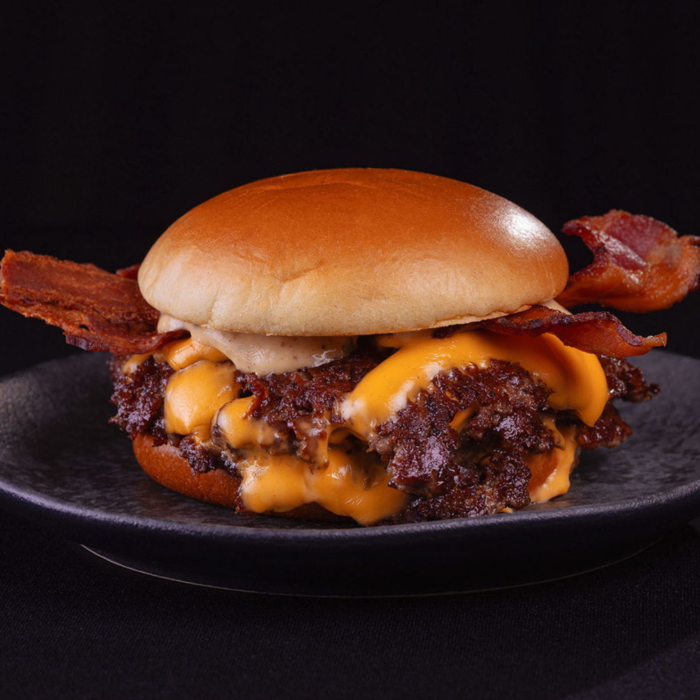 Três smashburgers de 80g, american cheese, bacon e molho cowboy no pão brioche.