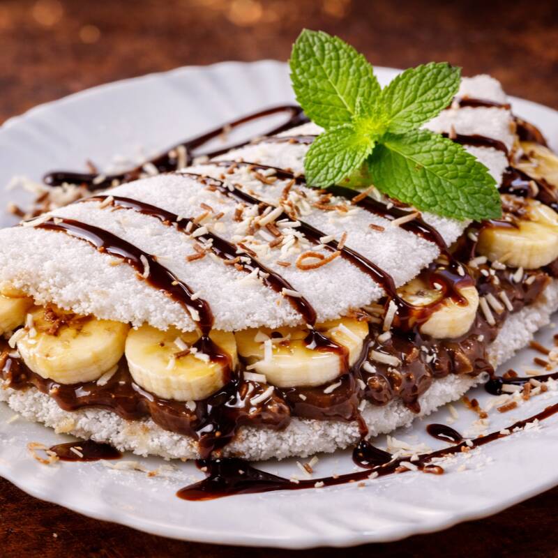 Se você ama doce na medida certa com aquela combinação que nunca falha, essa tapioca é pra você! A banana quentinha e macia se une ao chocolate cremoso, criando uma mistura perfeita entre o natural da fruta e a intensidade do chocolate. Cada mordida é equilibrada, envolvente e cheia de sabor. Não é à toa que é um dos sucessos do nosso cardápio! Uma tapioca doce que agrada adultos e crianças e deixa sempre aquele gostinho de “quero mais”. Peça agora e descubra por que essa combinação é uma das favoritas dos nossos clientes!