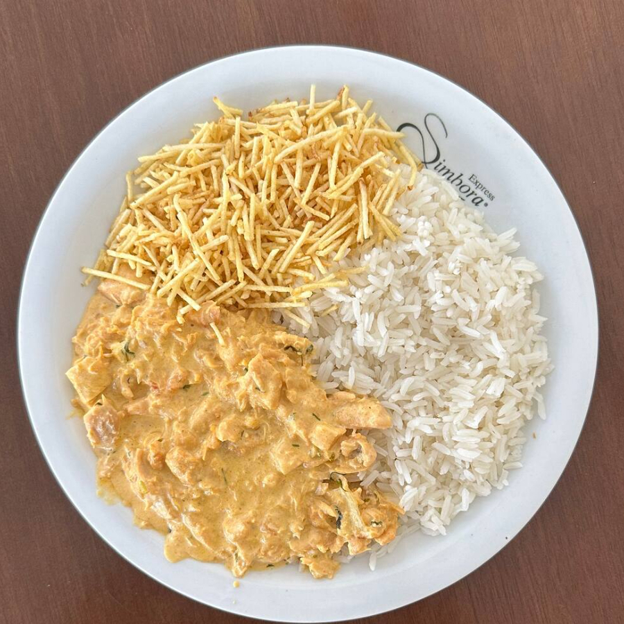 Nosso 'Marmita Strogonoff de Frango' é a opção ideal para aqueles que buscam uma refeição plenamente saborosa e gratificante. Apresenta um arroz meticulosamente cozido, estabelecendo uma base sublime para o nosso destacado segundo componente: a batata palha.
