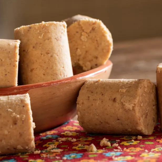 Doces tradicionais de amendoim moído em formato cilíndrico (rolha) dispostos sobre a mesa.