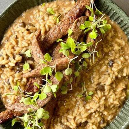 Arroz arbóreo preparado com vinho branco, manteiga, parmesão e funghi secci, acompanhado de tiras de alcatra.