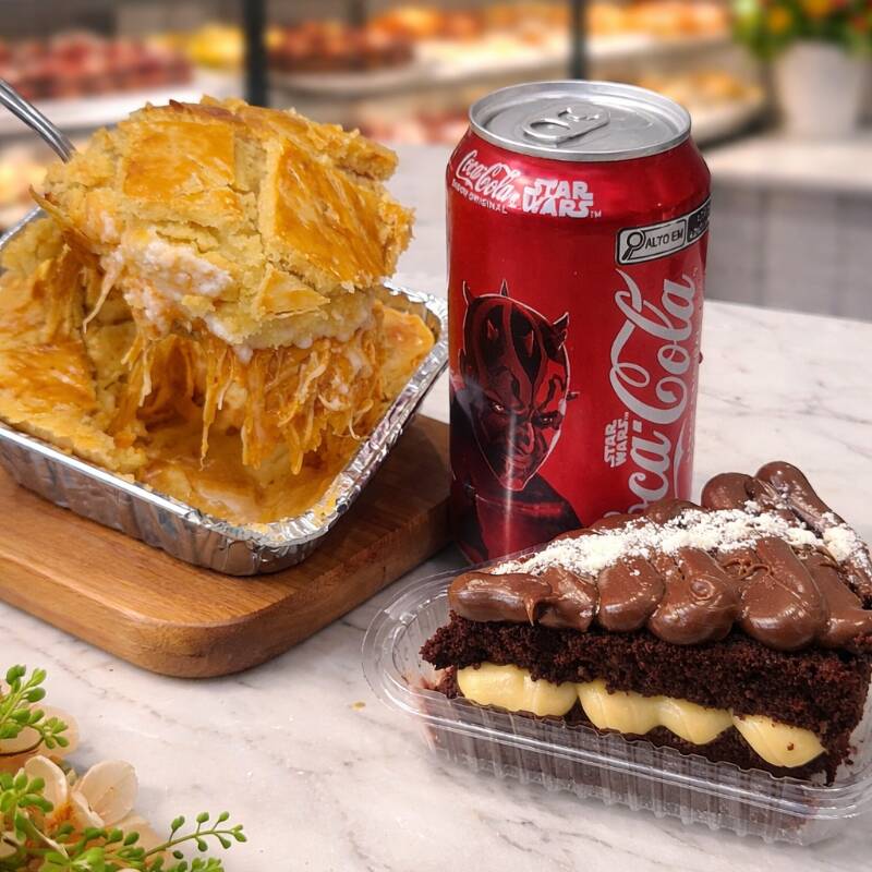 Empadão de frango com catupiry super cremoso, com massa leve e dourada que derrete na boca, acompanhado de uma fatia de bolo recheado bem molhadinho e uma Coca-Cola gelada para completar a experiência. Um combo perfeito para quem quer uma refeição completa, saborosa e irresistível.