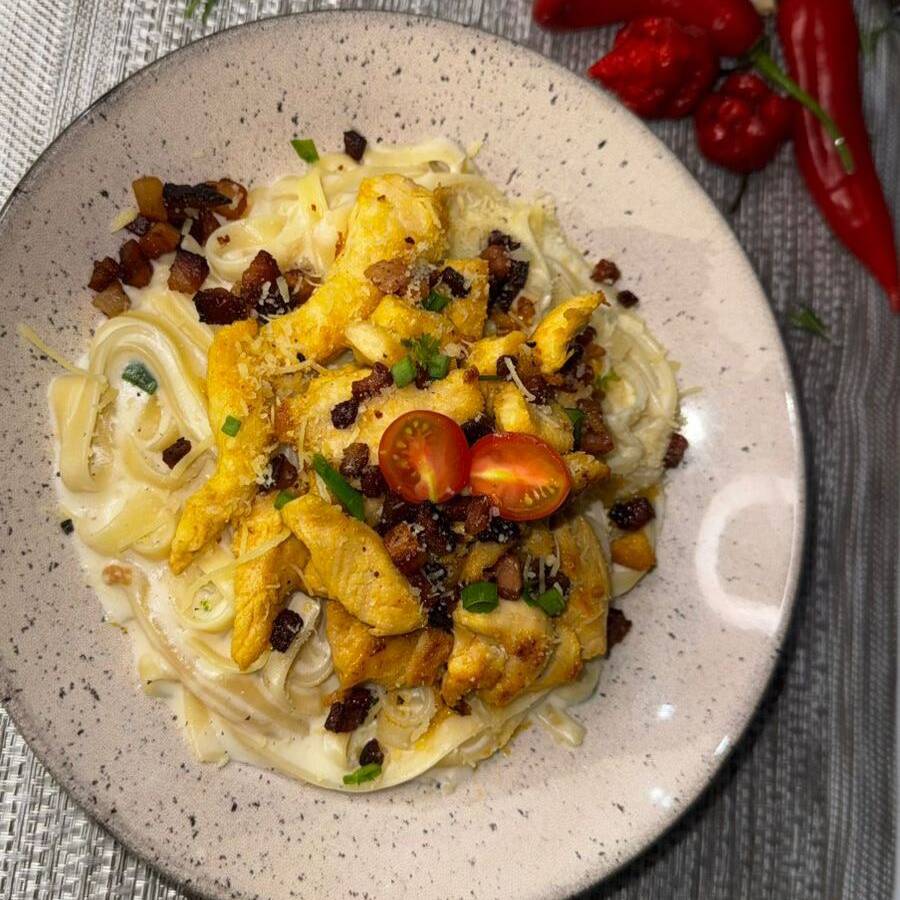 Peito de frango grelhado 160g, macarrão fettuccine ao molho alfredo, queijo parmesão e bacon em cubos.