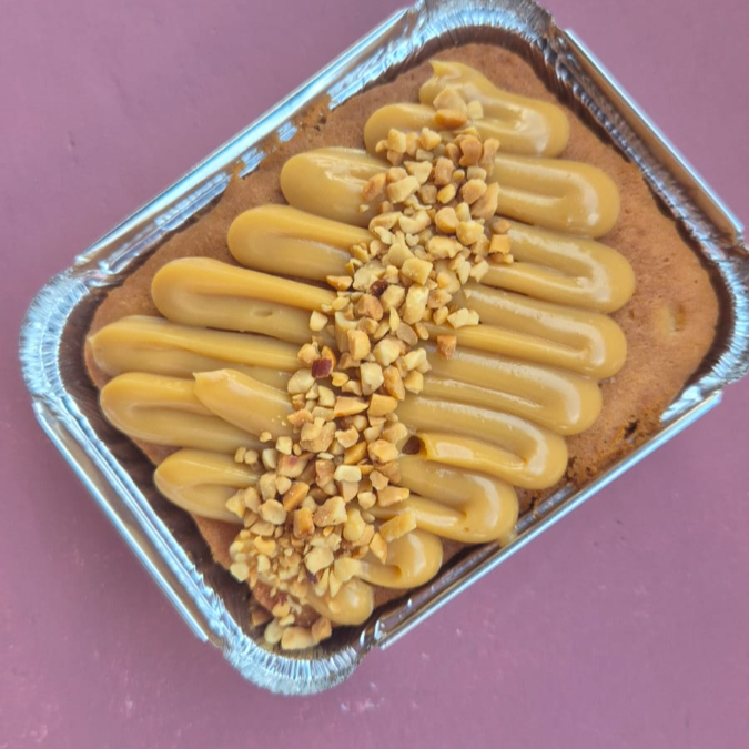 Bolo de massa amanteigada bem macia, coberto com doce de leite artesanal super cremoso e finalizado com xerém de amendoim crocante. Uma combinação que derrete na boca, com aquele toque caseiro e sabor que lembra infância. 🤎