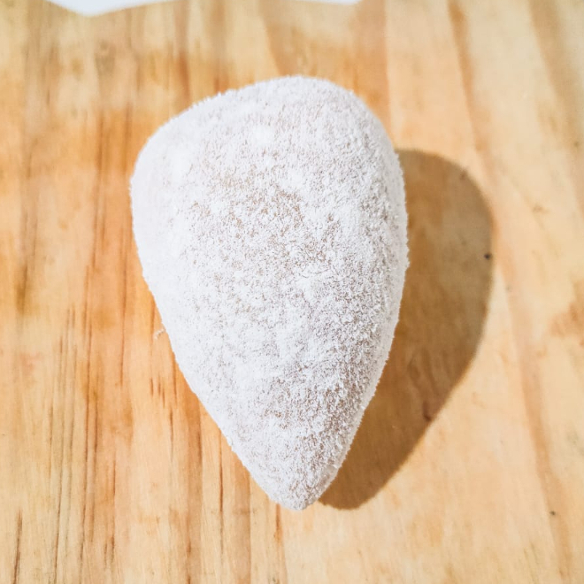 Coxinha de morango feita com brigadeiro de leite ninho cremoso, envolto em morango fresco e finalizado com leite em pó