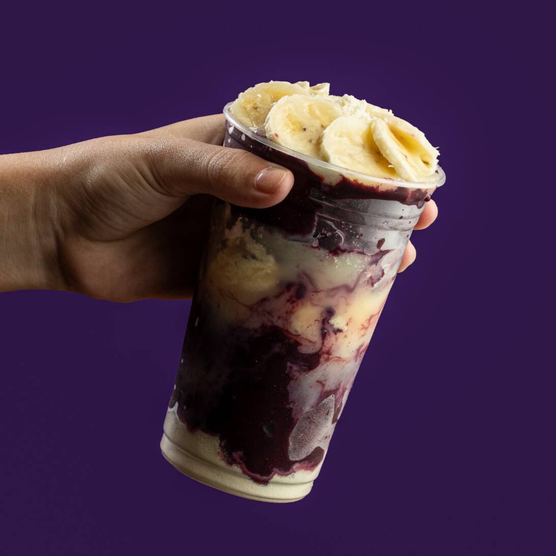 Creme de açaí acompanhado de banana, leite condensado e leite em pó no pote.