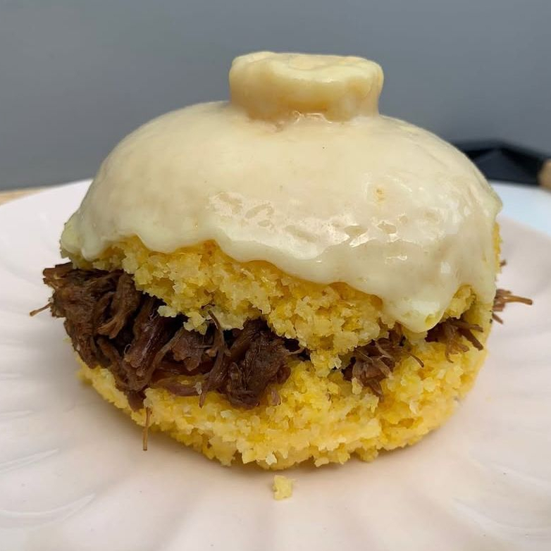 Cuscuz recheado com carne e finalizado com queijo mussarela.