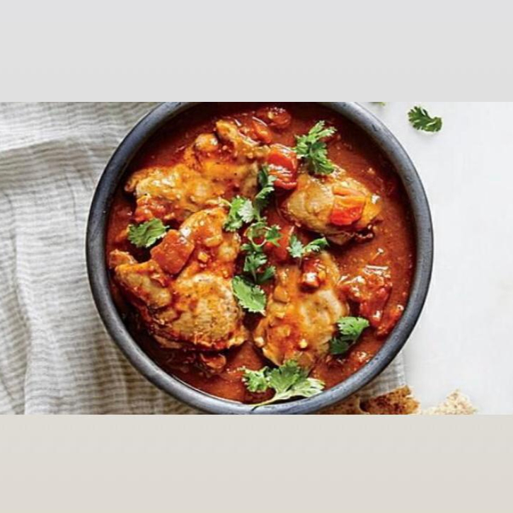 Pedaços de peito de frango marinados em iogurte, mergulhados em molho de iogurte, tomate, coentro e condimentos. Indicação da compra de um pão para acompanhamento.