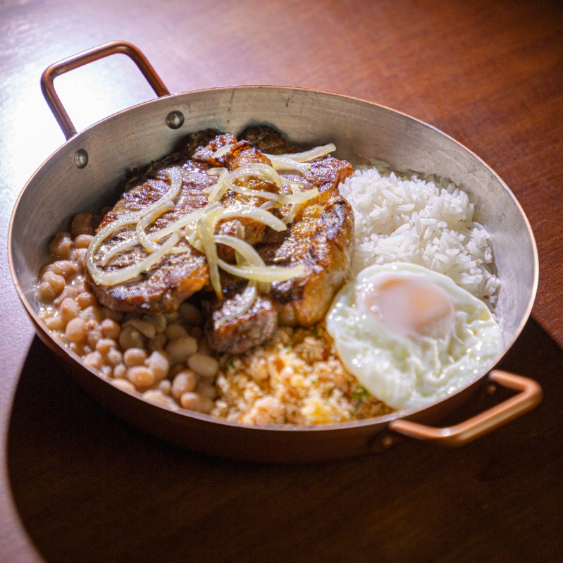 Contra filé acebolado, acompanha arroz branco, feijão de caldo, ovo frito e farofa d'água (farinha branca, coentro, manteiga do sertão, tomate, cebola, pimenta do reino).