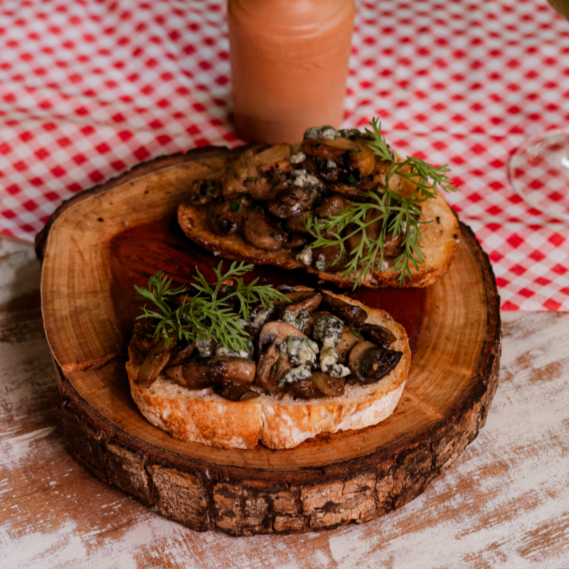 Fatias de pão Italiano de Fermentação Natural tostadas no azeite e aromatizadas com alho e cobertas com cogumelos frescos e Gorgonzola.